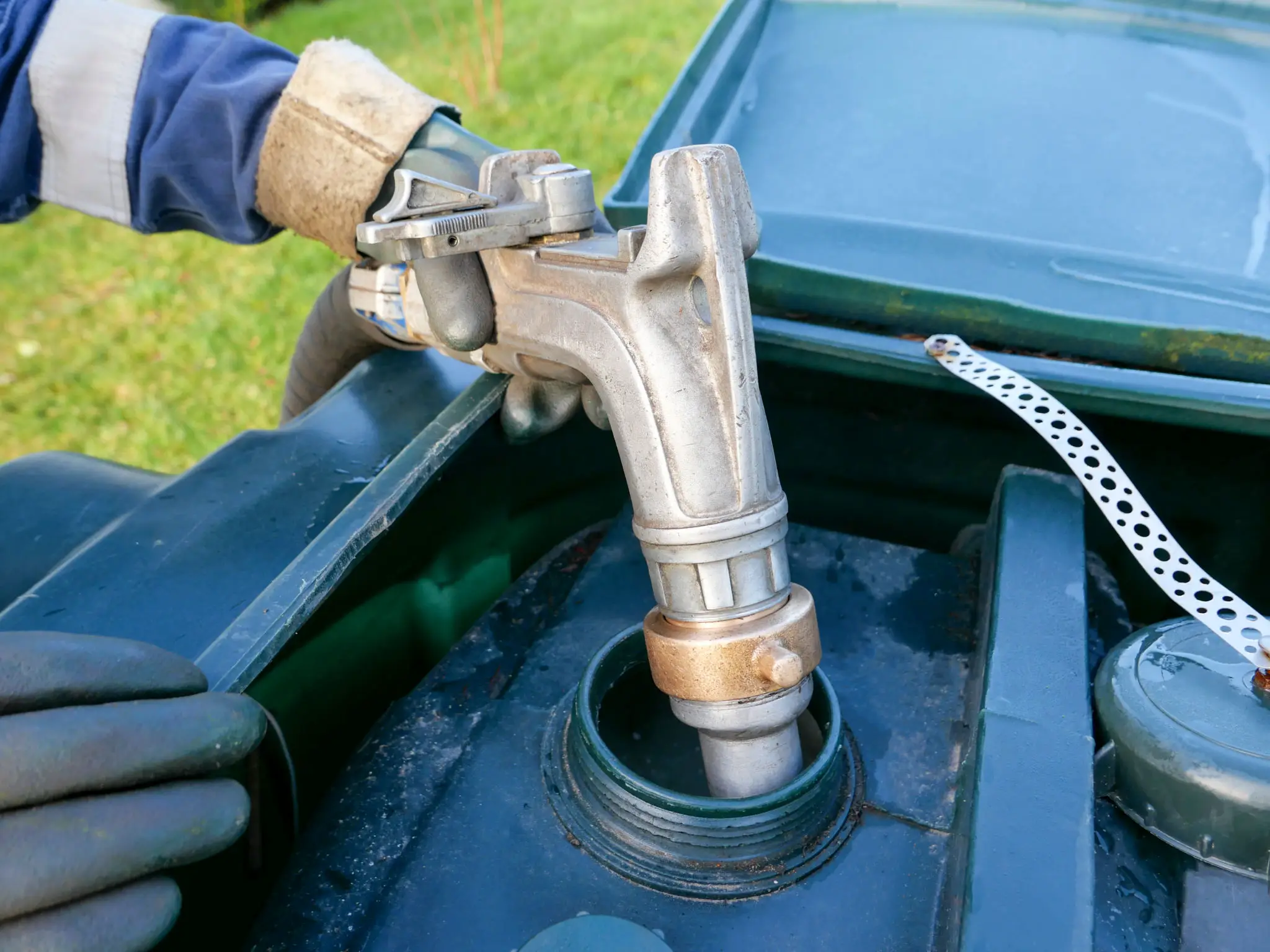 Person using a spray gun to clean a car's engine, with a metal object in the foreground